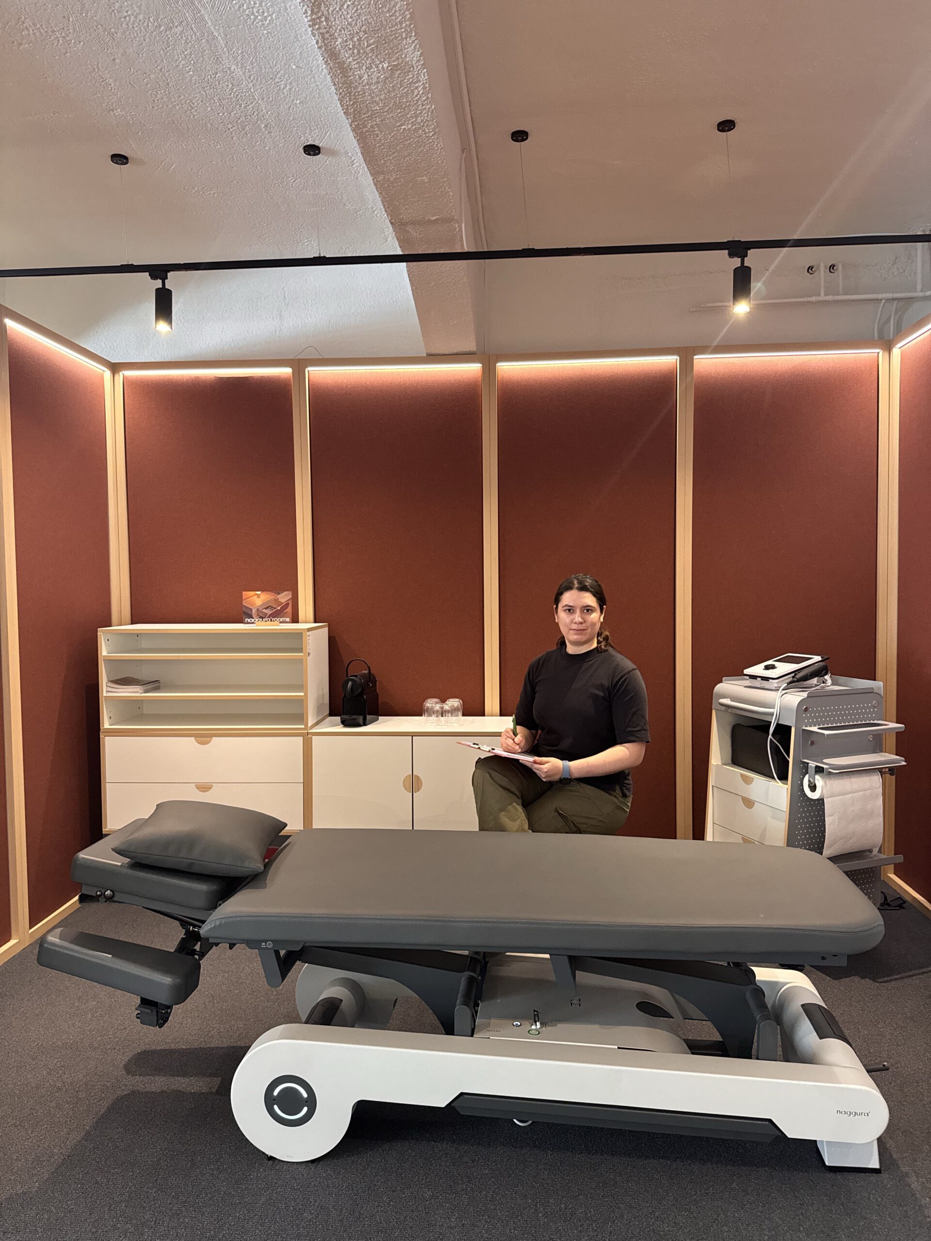 Therapeutin im Behandlungsraum mit elektrischer Therapieliege
